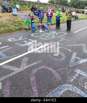 I bambini lo sfarinamento i nomi dei piloti su strada prima della data prevista di arrivo del Tour de France vicino Hawes, North Yorkshire, Inghilterra, Regno Unito Foto Stock