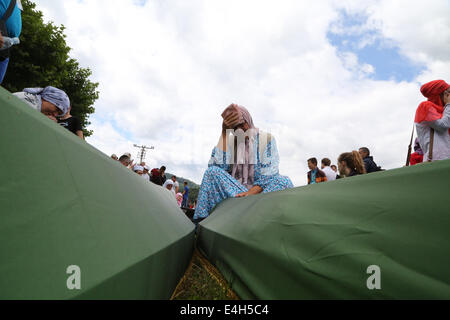 (140712) -- SREBRENICA, luglio 12, 2014 (Xinhua) -- una donna seduta accanto a bare delle vittime piange prima di un funerale in Potocari, vicino a Srebrenica, Bosnia e Erzegovina, 11 luglio, 2014. Il funerale di 175 recentemente identificate le vittime si è tenuto qui Venerdì per commemorare il diciannovesimo anniversario del massacro di Srebrenica. Alcuni 7.000 uomini musulmani e i ragazzi sono stati massacrati in e vicino a Srebrenica dalle forze serbo-bosniache nel luglio 1995, il peggior massacro in Europa dalla fine della Seconda Guerra Mondiale. (Xinhua/Haris Memija) (zjl) Foto Stock