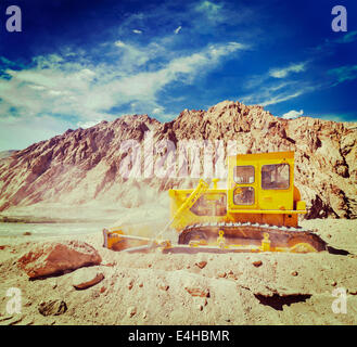 Vintage effetto retrò filtrata hipster stile immagine di viaggio di Bulldozer facendo strada in costruzione in Himalaya. Ladakh, Jammu e ka Foto Stock