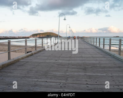 Ponte di legno che si estende verso l'oceano Foto Stock