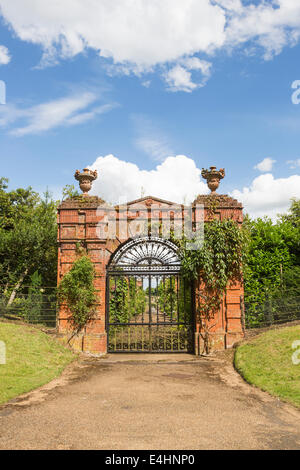 Arco in mattoni a vista e nero ferro battuto cancello per giardino murato di Sandringham House, Norfolk, Regno Unito con il cielo blu e nuvole bianche Foto Stock