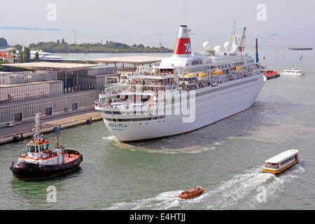 I passeggeri sul ponte della nave da crociera Fred Olsen Lines Boudicca sono trainati a ritroso in rimorchiatore fino alla nascita per la visita estiva al Porto di Venezia Italia Foto Stock