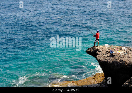 Uomo in piedi su sperone di roccia la pesca in mare a Playa Paraiso, Tenerife Foto Stock