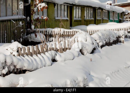 Case di legno ricoperta di neve Picket Fence garden Foto Stock