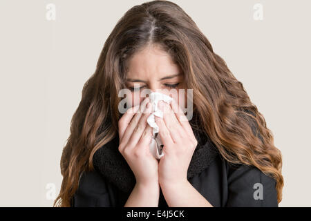 Pallida donna malata con un influenza, starnuti, in uno sfondo pulito Foto Stock