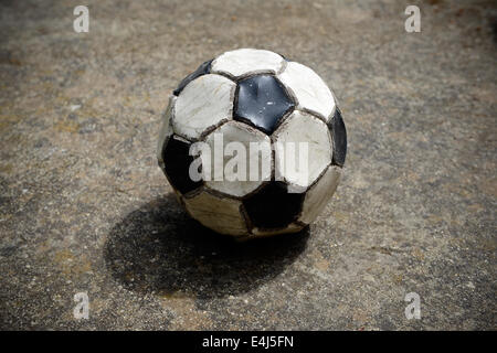 Vecchio e usato palla calcio su un cemento campo da gioco Foto Stock