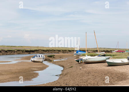 Barche spiaggiata con la marea in un fangoso creek di marea nel porto di Blakeney, un North Norfolk villaggio costiero, REGNO UNITO Foto Stock