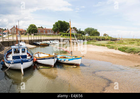 Barche ormeggiate nel torrente nel porto di Blakeney, costiere a nord di Norfolk, Regno Unito in estate con nuvoloso cielo blu Foto Stock