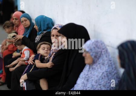 La striscia di Gaza, Israele. 13 Luglio, 2014. Le donne palestinesi, che sono fuggiti dalla loro casa vicino al confine con Israele, soggiorno presso le Nazioni Unite-run scuola nella città di Gaza il 13 luglio 2014. Le incursioni aeree israeliane hanno ucciso 156 vive e ferito altri 1,065 dal martedì. Credito: Wissam Nassar/Xinhua/Alamy Live News Foto Stock