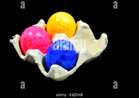 Tre colorate uova di pasqua in una scatola di cartone, vicino, isolati su sfondo nero