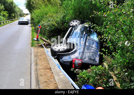 West Wittering, West Sussex, Regno Unito. 13 Luglio, 2014. Range Rover Freelander 2 supporti cordolo rompe attraverso il ponte di legno rotaie finisce in un piccolo ruscello presso la strada di accesso al West Wittering Parcheggio Auto. Le ambulanze sono state sulla scena. La causa non è noto o se qualsiasi lesione sustainedPhotograph Gary Blake/Alamy Live Live News Foto Stock