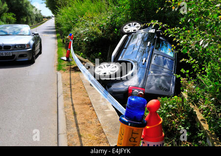 West Wittering, West Sussex, Regno Unito. 13 Luglio, 2014. Range Rover Freelander 2 supporti cordolo rompe attraverso il ponte di legno rotaie finisce in un piccolo ruscello presso la strada di accesso al West Wittering Parcheggio Auto. Le ambulanze sono state sulla scena. La causa non è noto o se qualsiasi lesione sustainedPhotograph Gary Blake/Alamy Live Live News Foto Stock