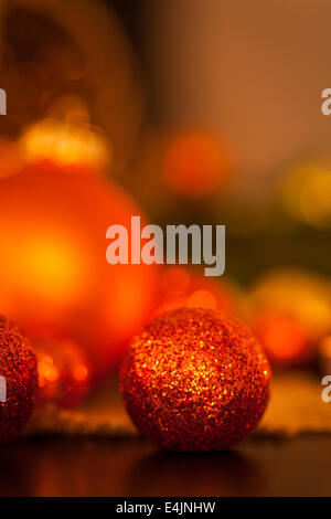 Caldo oro e rosso il Natale a lume di candela con sottofondo di masterizzazione luci tè tra oro casuale e baubles rosso in un caldo incandescente Foto Stock