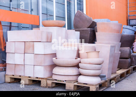 Vetri e ceramiche non smaltate vasi da fiori in una varietà di dimensioni e colori impilati su pallet di legno al di fuori di una ceramica, magazzino Foto Stock