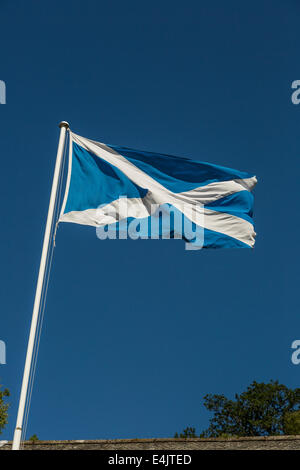 La Scozia si intraversa bandiera nel vento con un cielo blu scuro dello sfondo. Foto Stock
