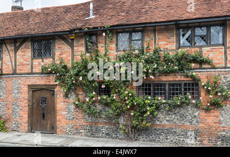 In mattoni rossi costruito con travi di legno villette a schiera a Henley-on-Thames, Oxfordshire, Regno Unito, con belle le rose rosa attorno alle finestre Foto Stock