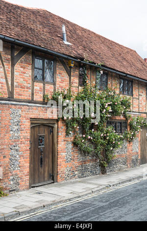 In mattoni rossi costruito con travi di legno bungalow a schiera a Henley-on-Thames, Oxfordshire, Regno Unito, con belle le rose rosa attorno alle finestre Foto Stock