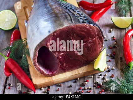 Crudo fresco di coda di tonno su tavola di legno con red hot chili pepper, lime fresco e aneto. Messa a fuoco selettiva. Foto Stock