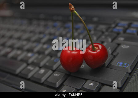 Ciliegia fresca sulla tastiera del notebook Foto Stock