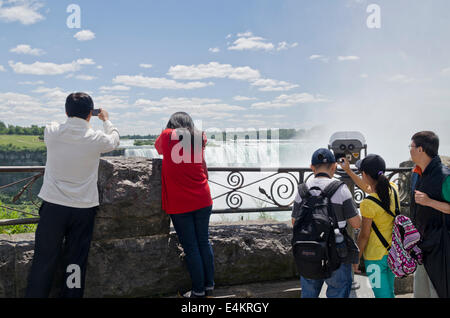 Famiglia di turisti asiatici che visitano e fotografano le Cascate del Niagara dal lato canadese in una giornata di sole estate. Foto Stock