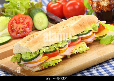 Baguette sottomarino insalata sandwich con prosciutto formaggio e pomodoro sul tagliere di legno Foto Stock