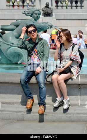 Londra, Inghilterra, Regno Unito. Giovani asiatici giovane rilassante in Trafalgar Square Foto Stock