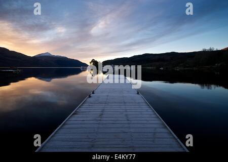 La pre-sunrise colori su ancora un Loch Lomond con il molo a inveruglus conduce in loch Foto Stock