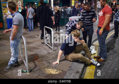 Un giovane uomo malato in pubblico (dopo il vomito) in un fine settimana la notte a Cardiff, nel Galles, Regno Unito Foto Stock