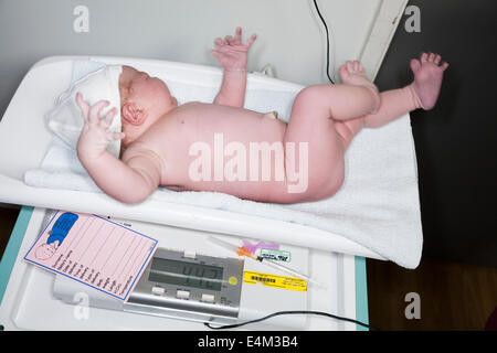 La pesatura di un neonato / new born baby con bilance / scala subito dopo il parto / parto in un ospedale di NHS. Foto Stock