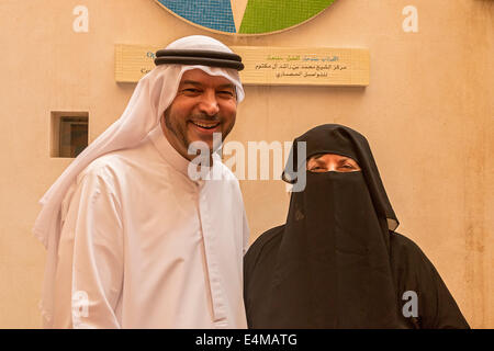 Guida musulmana Nasif Kayed, in un tradizionale tunica araba e copricapo, aiuta a visitare donna americana provare sulla tradizionale abaya robe Foto Stock