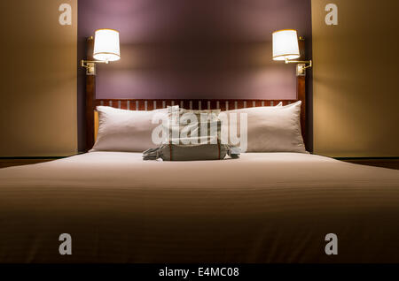 Letto con cuscini e lampade da parete Foto Stock