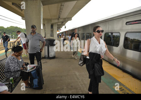 Merrick, New York, Stati Uniti d'America. 14 Luglio, 2014. In serata durante le ore di punta, una donna in business suit e altri passeggeri di lasciare il treno mentre altri attendere per treni di arrivare sulla piattaforma sopraelevata di Merrick stazione ferroviaria di Babilonia il ramo, dopo MTA Metropolitan Transit Authority e Long Island Rail Road unione parla deadlock, con potenziale sciopero LIRR aleggiano pochi giorni prima. © Ann Parry/ZUMA filo/Alamy Live News Foto Stock