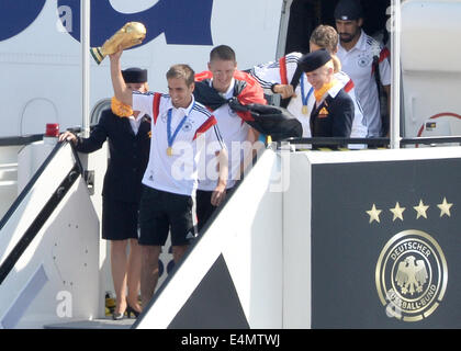 Berlino, Germania. Il 15 luglio 2014. Germania Philipp Lahm ( C), seguito dai suoi compagni di squadra Bastian SCHWEINSTEIGER e Thomas Mueller (R), passo fuori del velivolo che tiene il mondo Cup Trofeo nelle sue mani come la Germania nazionale della squadra di calcio arriva presso l'aeroporto di Tegel a Berlino, Germania, 15 luglio 2014. Team Germany ha vinto il Brasile 2014 FIFA Soccer finale di Coppa del Mondo contro l'Argentina da 1-0, vincendo il titolo di Campione del Mondo per la quarta volta dopo il 1954, 1974 e 1990 Coppe del mondo. Foto: BERND VON JUTRCZENKA/dpa/Alamy Live News Foto Stock