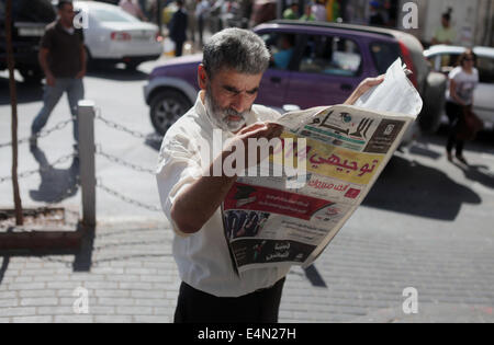 Ramallah, West Bank, Territorio palestinese. Il 15 luglio 2014. Un uomo palestinese legge un giornale locale per trovare i risultati di alta scuola gli studenti in Cisgiordania città di Ramallah il 24 luglio 2011. Foto Stock
