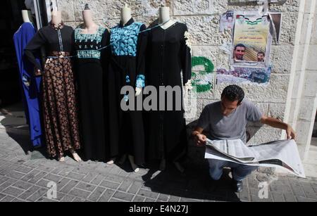 Ramallah, West Bank, Territorio palestinese. Il 15 luglio 2014. Un uomo palestinese legge un giornale locale per trovare i risultati di alta scuola gli studenti in Cisgiordania città di Ramallah il 24 luglio 2011. Foto Stock