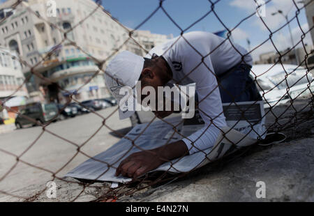 Ramallah, West Bank, Territorio palestinese. Il 15 luglio 2014. Un palestinese di alta scuola studente legge un giornale locale per trovare i suoi risultati in Cisgiordania città di Ramallah il 24 luglio 2011. Foto Stock