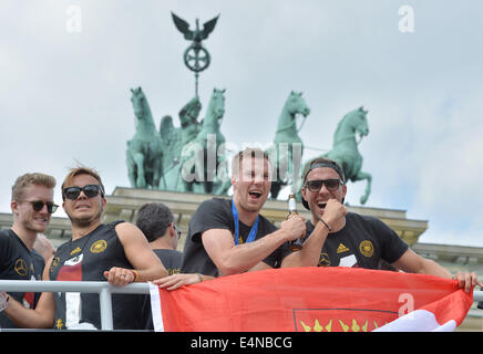 Berlino, Germania. Il 15 luglio 2014. In Germania i giocatori Andre Schuerrle (L-R), Mario Goetze, Kevin Großkreutz e Lukas Podolski wave e allegria ai tifosi come allenatore con la Germania la nazionale di calcio arriva al cosiddetto "Ventilatore Meile' davanti alla Porta di Brandeburgo, Berlino, Germania, 15 luglio 2014. Il team tedesco ha vinto il Brasile 2014 FIFA Soccer finale di Coppa del Mondo contro l'Argentina da 1-0 il 13 luglio 2014, vincendo il titolo di coppa del mondo per la quarta volta dopo il 1954, 1974 e 1990. Foto: HENDRIK SCHMIDT/dpa/Alamy Live News Foto Stock