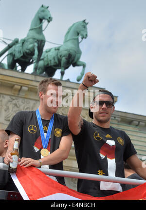 Berlino, Germania. Il 15 luglio 2014. In Germania i giocatori Kevin Grosskreutz (L) e Lukas Podolski wave e allegria ai tifosi come allenatore con la Germania la nazionale di calcio arriva al cosiddetto "Ventilatore Meile' davanti alla Porta di Brandeburgo, Berlino, Germania, 15 luglio 2014. Il team tedesco ha vinto il Brasile 2014 FIFA Soccer finale di Coppa del Mondo contro l'Argentina da 1-0 il 13 luglio 2014, vincendo il titolo di coppa del mondo per la quarta volta dopo il 1954, 1974 e 1990. Foto: HENDRIK SCHMIDT/dpa/Alamy Live News Foto Stock