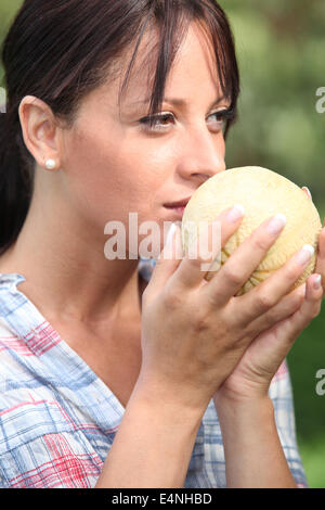 Giovane donna odorare un melone Foto Stock