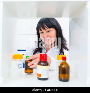 Il farmacista di prendere la medicina bottiglia dal cabinet Foto Stock