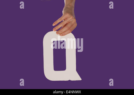 Mano che tiene la lettera Q dalla parte superiore Foto Stock