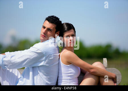 Coppia giovane sat back to back sul banco di lavoro Foto Stock