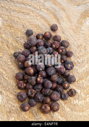 Cumulo di essiccato bacche di ginepro su cucina in legno board Foto Stock