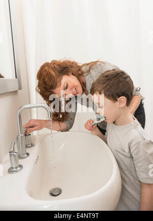 Figlio (6-7) e la madre la spazzolatura dei denti Foto Stock