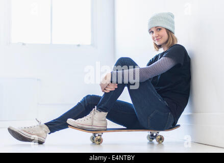 Ritratto di giovane donna seduta su skateboard Foto Stock