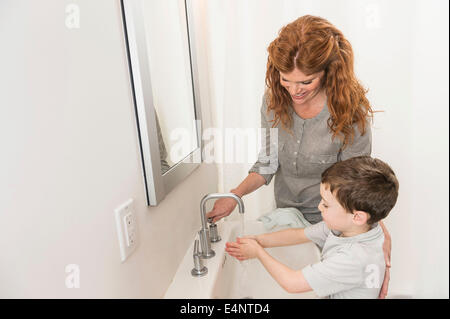 Figlio (6-7) e madre lavaggio delle mani Foto Stock