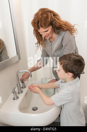 Figlio (6-7) e madre lavaggio delle mani Foto Stock