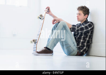 Ragazzo adolescente (16-17) azienda skateboard Foto Stock