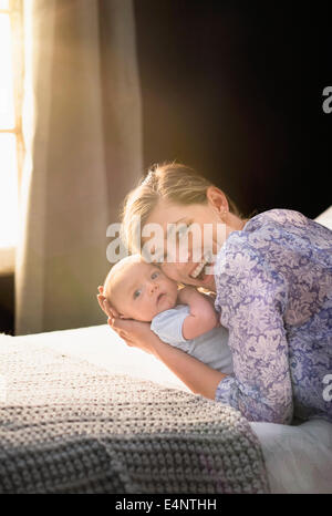 Ritratto di Madre sorridente holding baby boy (2-5 mesi) in camera da letto Foto Stock