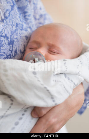 Close up baby boy (2-5 mesi) dormire nella madre di braccia Foto Stock